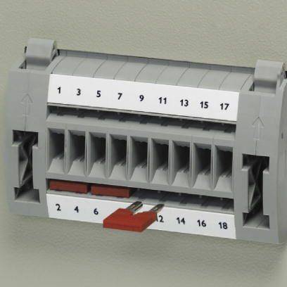 Graue elektrische Klemme mit nummerierten Anschlusspunkten von 1 bis 18. Zwei rote Brücken sind bei den Zahlen 2, 6 und 4, 8 eingesteckt.