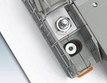 Ein graues Verbindungselement mit Schraube und Mutter, montiert auf einer weißen Oberfläche, zeigt industrielle Befestigungstechnik.