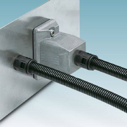 Ein rechteckiger Stecker an einer Metallwand, verbunden mit zwei schwarzen Kabeln, die aus dem Stecker herausführen. Die Umgebung ist schlicht.