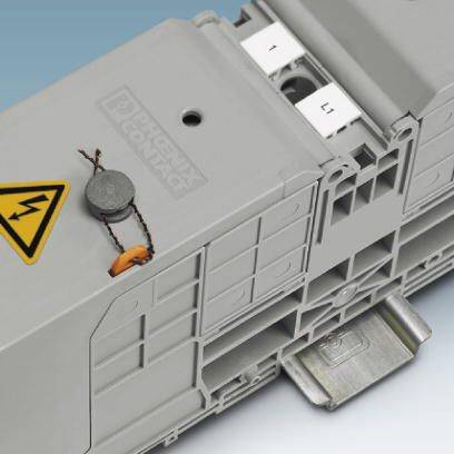 Graues elektrisches Bauteil mit Warnzeichen für hohe Spannung, auf einer Metallhalterung montiert. Geeignet für technische Installationen.