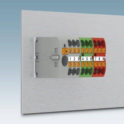 Eine Klemmleiste mit mehrfach farbcodierten elektrische Klemmen, nummeriert von 1 bis 9, an einer silbernen Montageplatte.