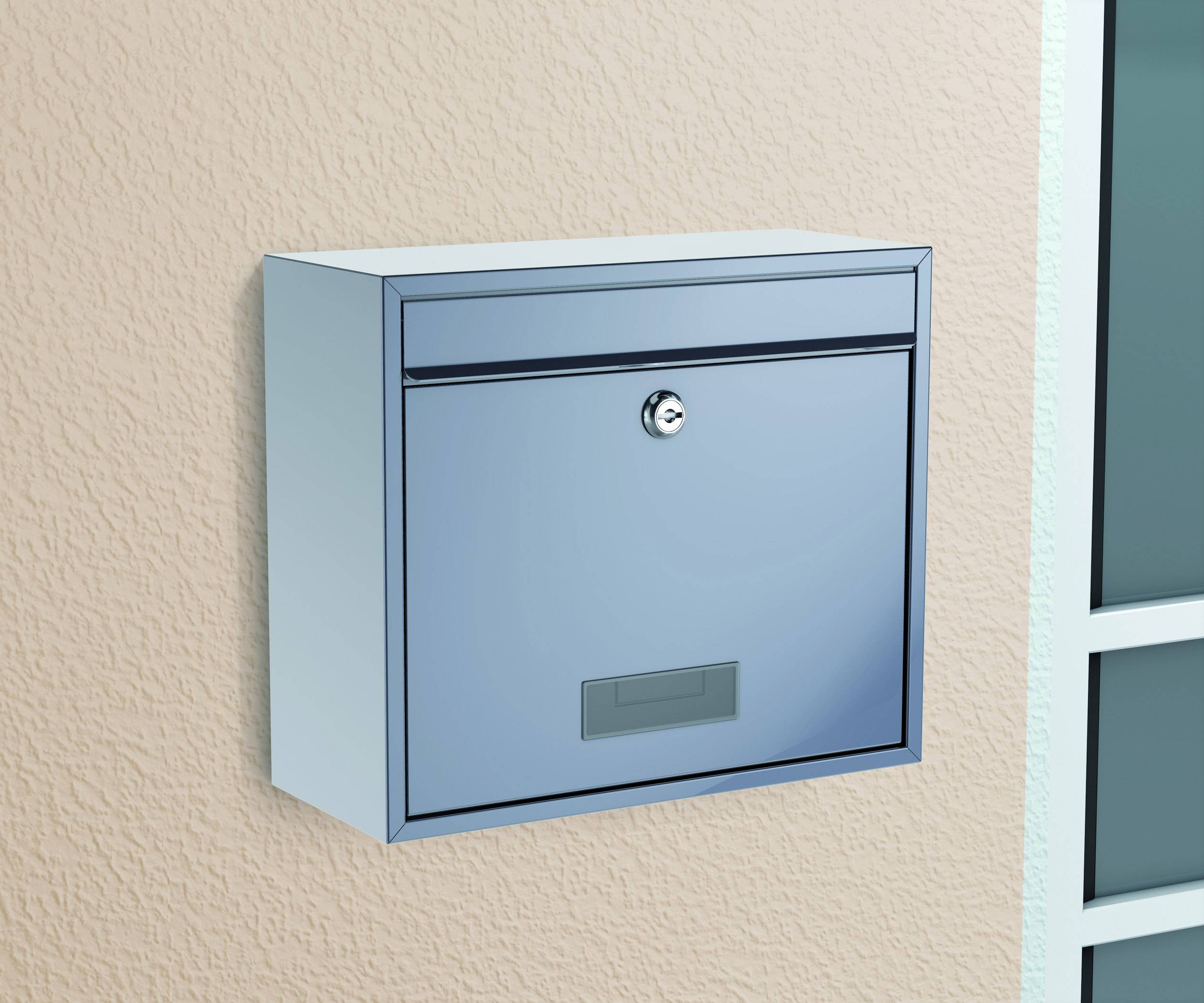 Ein blauer Briefkasten an einer beigefarbenen Wand neben einem Fenster. Der Briefkasten hat ein Schloss und eine Namensschildhalterung.