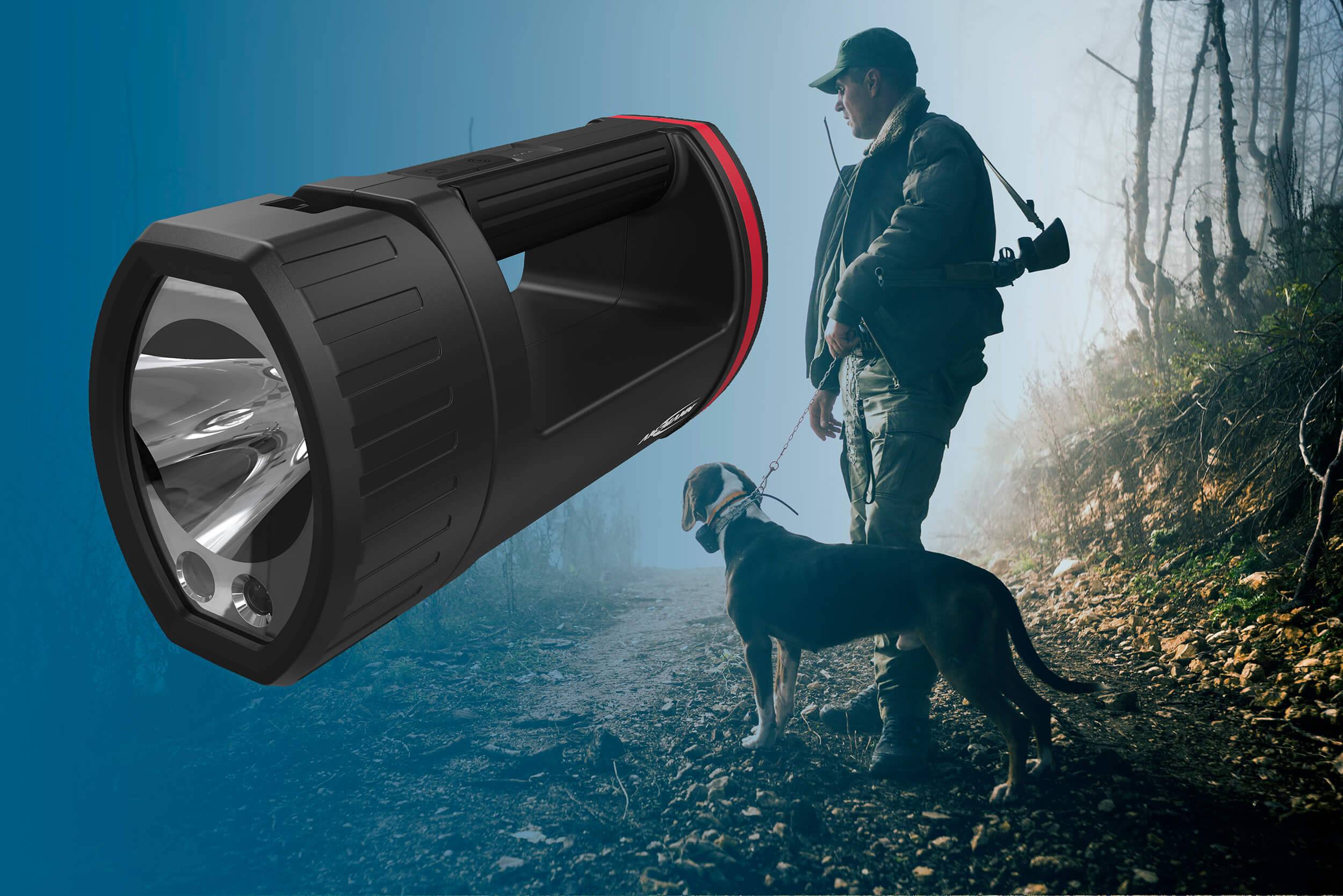 Eine Person mit Hund im Wald bei Dämmerung, trägt Jagdausrüstung. Im Vordergrund scheint eine große Taschenlampe.