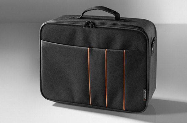 Eine schwarze, rechteckige Tasche mit Griff, orangen Nähten und mehreren Fächern auf einem grauen Hintergrund.