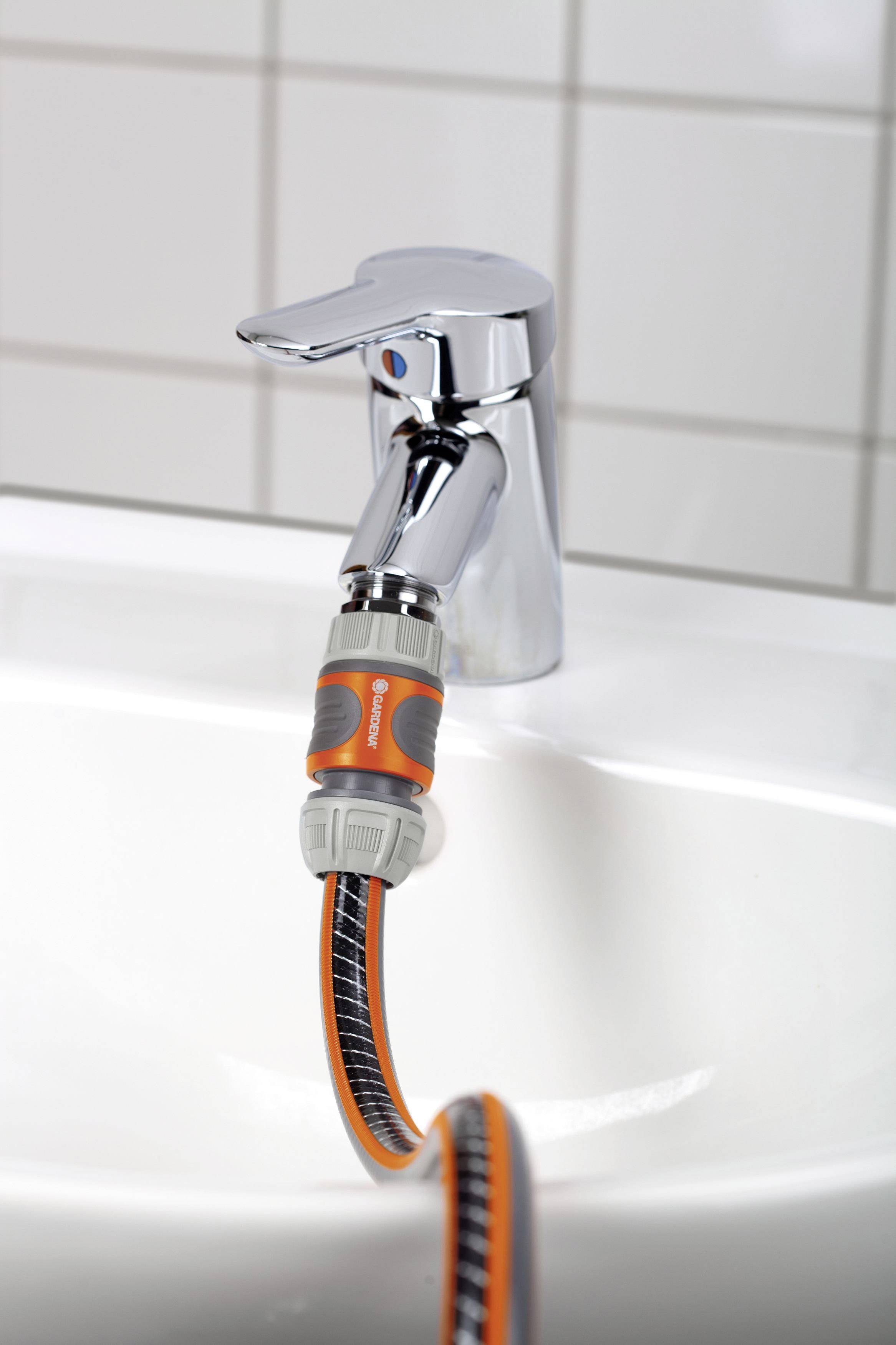 Ein Wasserhahn mit einem angeschlossenen Gartenschlauchadapter zeigt eine effiziente Möglichkeit, einen Gartenschlauch mit dem Innenbereich zu verbinden.