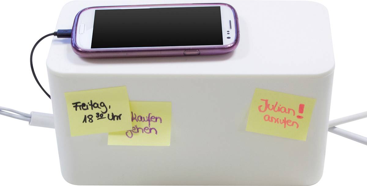 Ein Smartphone liegt auf einer weißen Box. Auf der Box sind drei Klebezettel mit Notizen: 'Freitag, 18:00 Uhr' und 'Julian anrufen!'.