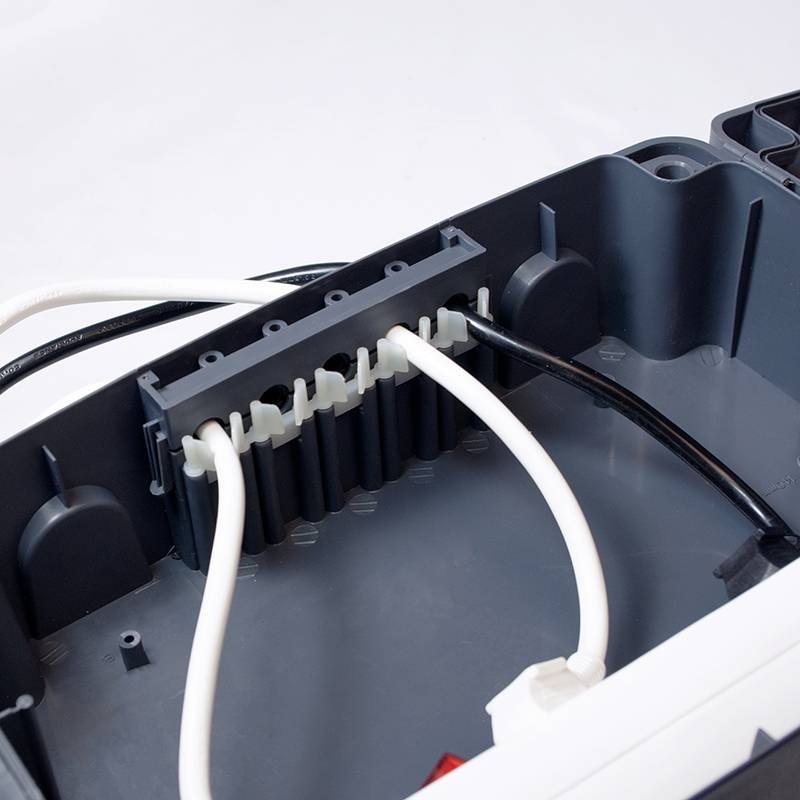 Ein geöffnetes elektrisches Gehäuse mit mehreren angeschlossenen Kabeln, darunter schwarzes und weißes Kabel.