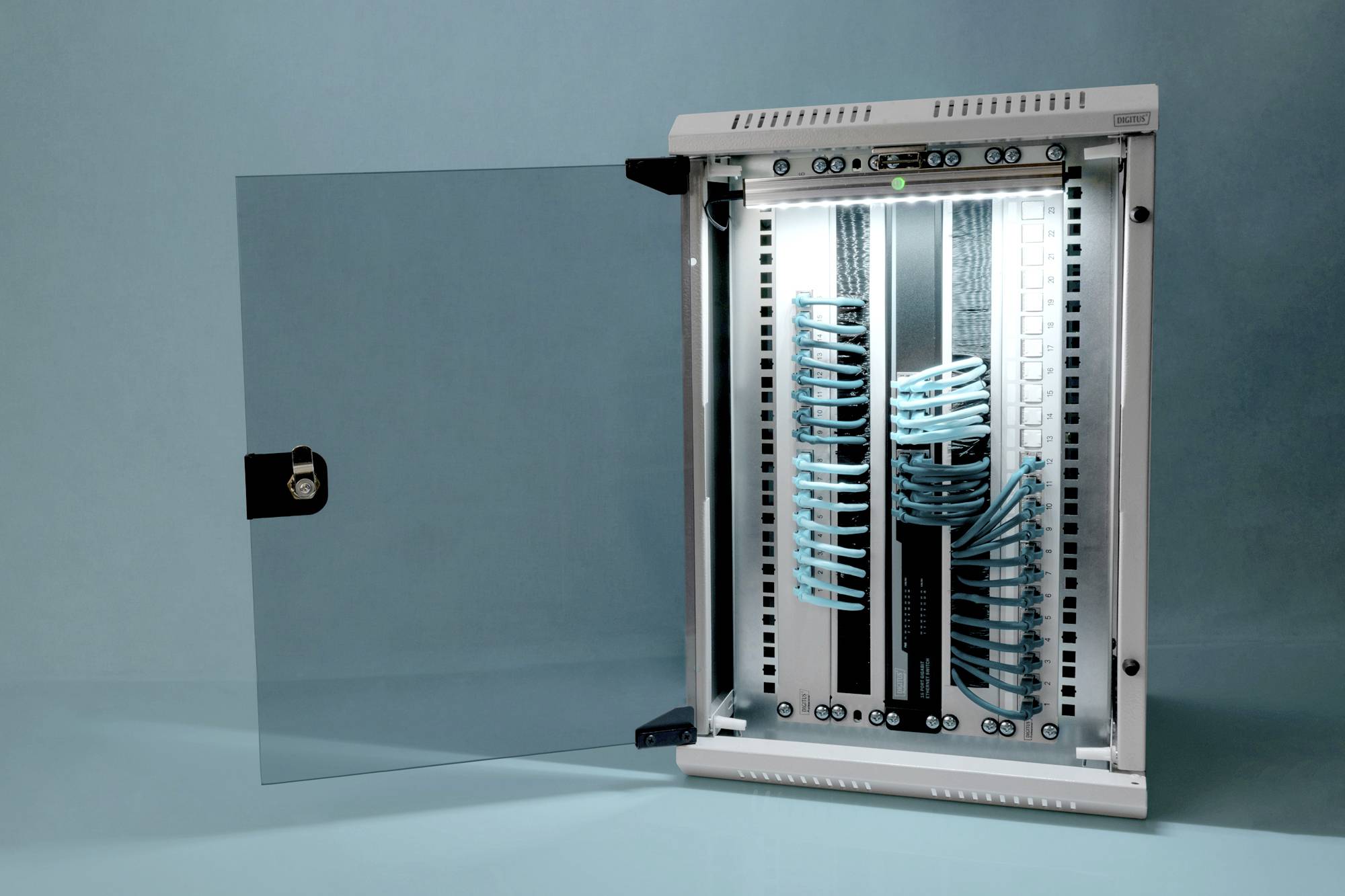 Offener Serverschrank mit ordentlich verlegten blauen Netzwerkkabeln, die an Patchpanels angeschlossen sind, vor blauem Hintergrund.