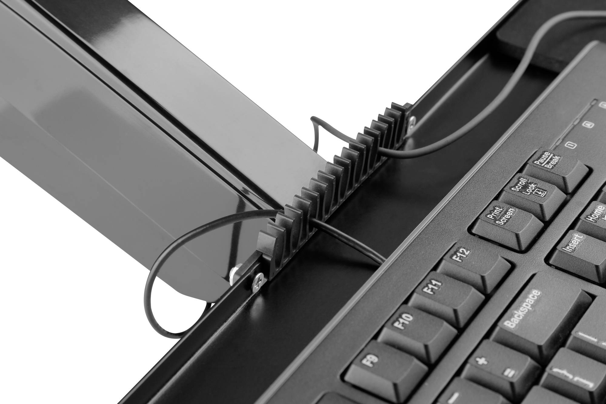 Nahaufnahme einer Computertastatur mit Kabeln, die durch eine Kabelmanagementvorrichtung geführt sind.