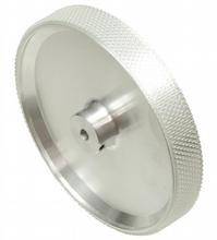 Ein silbernes, gerändeltes Rad oder Drehknopf aus Metall, vermutlich ein Maschinenteil, mit zentraler Achsbohrung.