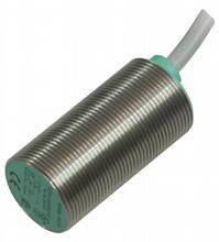 Ein zylindrischer Näherungssensor aus Metall mit geriffelter Oberfläche und grüner Anschlussabdeckung, von einem Kabel abgehend.