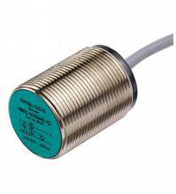 Ein zylindrischer induktiver Näherungssensor mit grünem Kopf und Metallgehäuse, verbunden mit einem grauen Kabel.