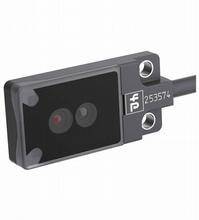 Ein rechteckiger Sensor mit zwei Linsen und einer Nummer '253574'. Der Sensor hat ein schwarzes Gehäuse mit Schraubbefestigungen auf der rechten Seite.