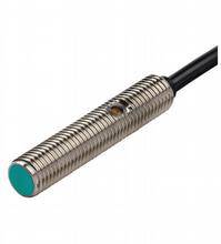 Zylindrischer induktiver Sensor mit Metallgehäuse und schwarzem Kabel. Wird zur Erkennung von Objekten durch elektromagnetische Felder verwendet.