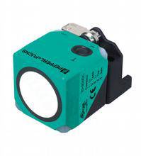Ein quadratischer, grüner Sensor mit einem runden weißen Element und Anschluss an der Oberseite.