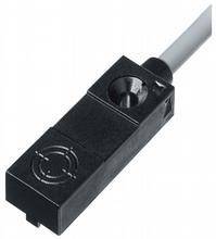 Schwarzer Sensor mit Kabelanschluss, rechteckige Form, und ein kreisförmiges Symbol auf der Oberfläche. Verwendung in technischen Anwendungen.