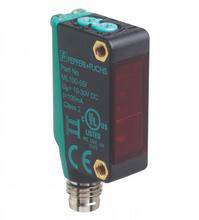 Ein rechteckiger, schwarzer Sensor mit grüner Aufschrift, rotem Lichtsensor und silbernem Anschluss. Entwickelt für industrielle Anwendungen.