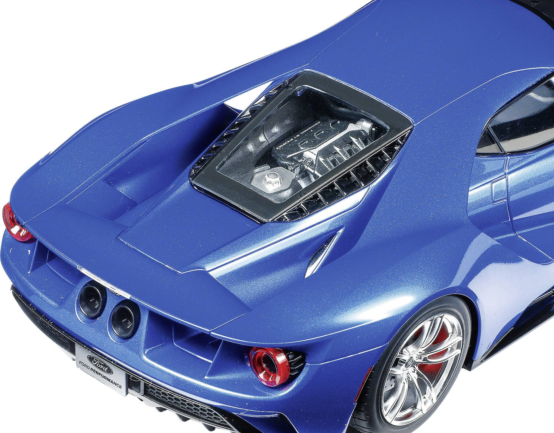 Ein blauer Sportwagen von oben abgebildet. Sichtbar sind der Motor durch eine durchsichtige Abdeckung, Doppelauspuff und Heckleuchten.