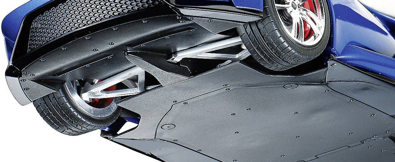 Untere Ansicht eines Autos zeigt komplexes Fahrwerksdesign und Radaufhängung. Fahrzeugfarbe blau, Felgen silbern, Hintergrund neutral.