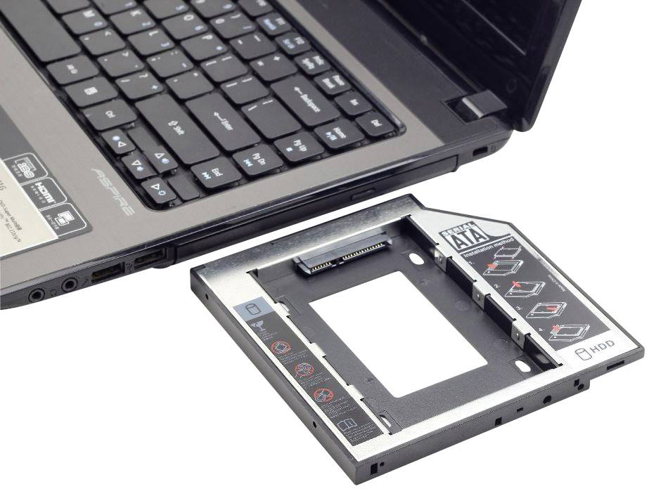 Laptop mit Tastatur und offenem Festplattenschacht; daneben ein Adapter für den Einbau einer zusätzlichen HDD/SSD.
