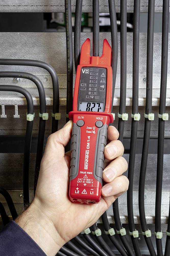 Ein Hand hält ein digitales Spannungsprüfgerät zwischen mehreren schwarzen Kabeln. Das Display zeigt den Messwert an.