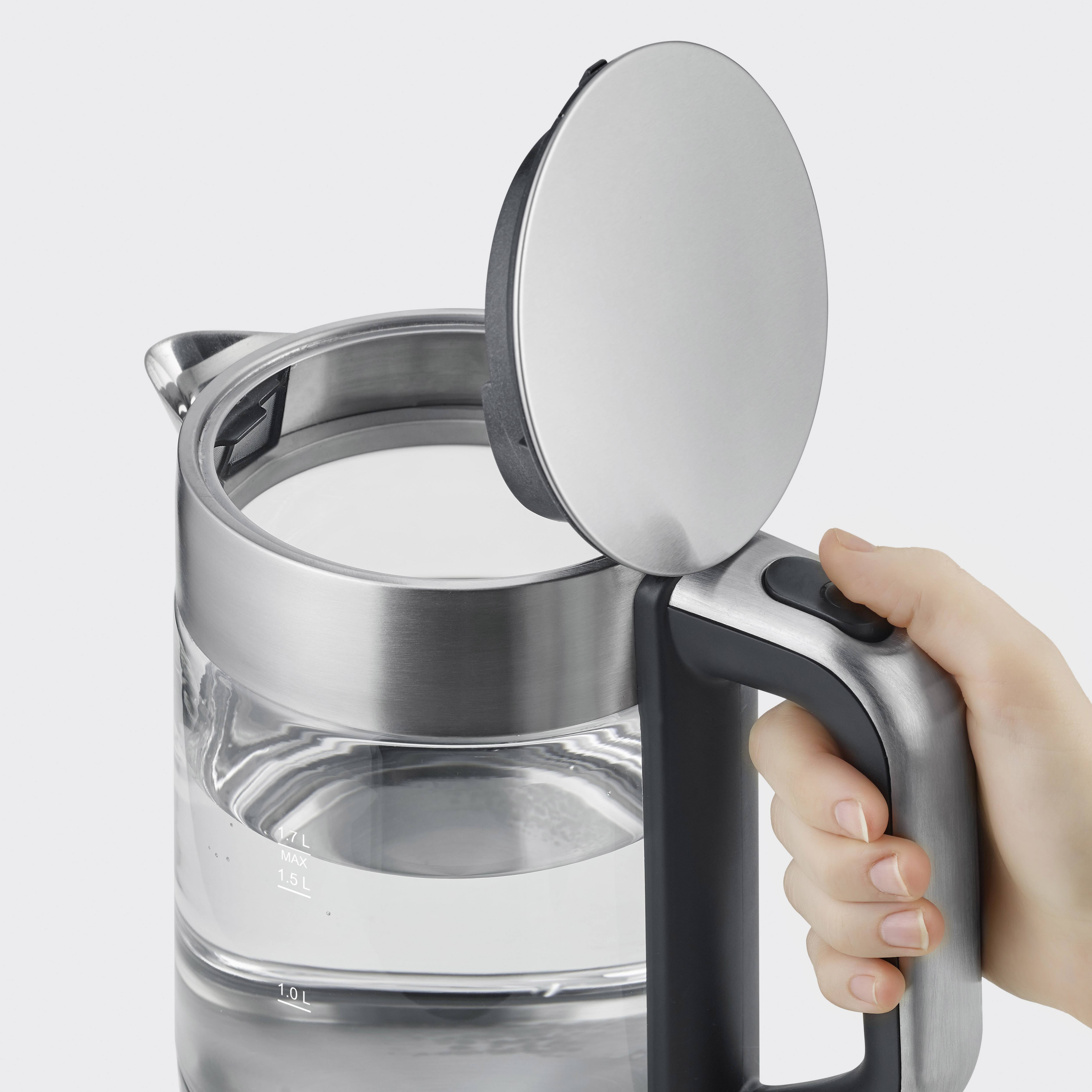Wasserkocher mit geöffnetem Deckel, gefüllt mit Wasser. Eine Hand hält den Griff. Der Wasserstand ist durch die transparente Wand sichtbar.