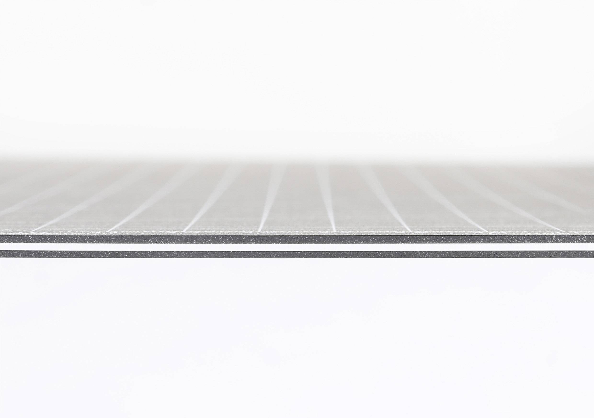 Nahaufnahme einer geriffelten, grauen Materialoberfläche, möglicherweise eine Metallplatte mit feinen Linien. Heller Hintergrund.