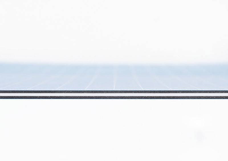 Nahaufnahme einer dünnen, horizontalen, mehrschichtigen Oberfläche, bei der die Schichten klar zu erkennen sind, vor einem weißen Hintergrund.