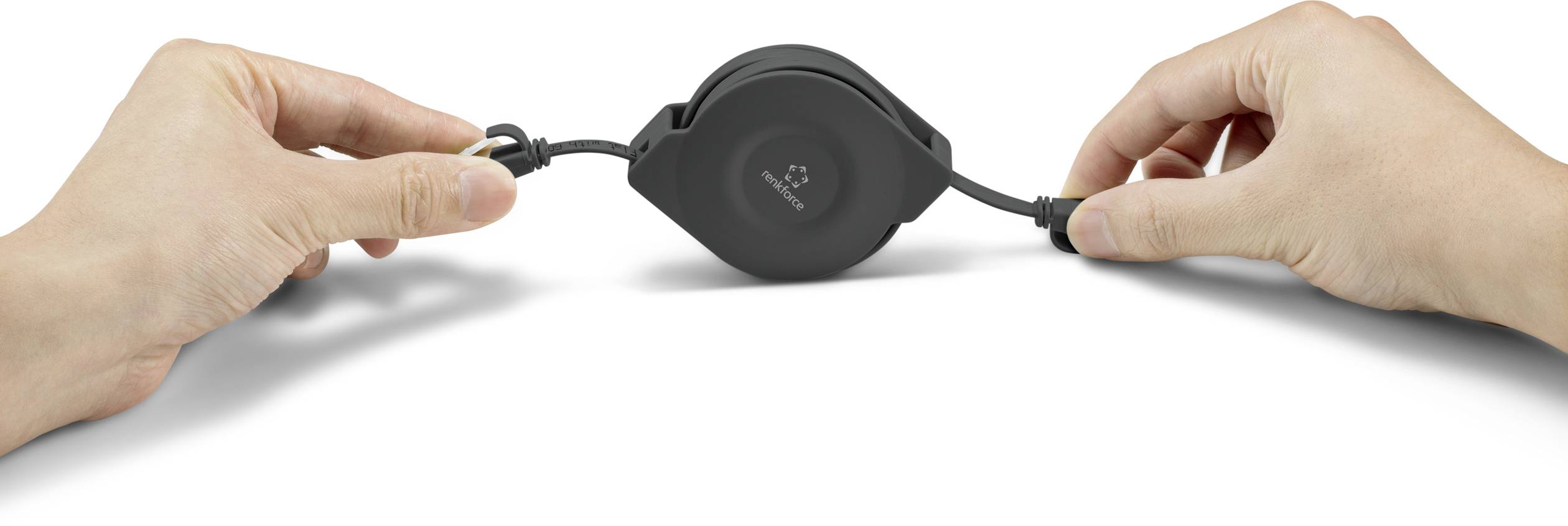 Zwei Hände ziehen an einem schwarzen, einziehbaren Kabelaufroller. Die eine Hand hält den Stecker, die andere das Gehäuse.