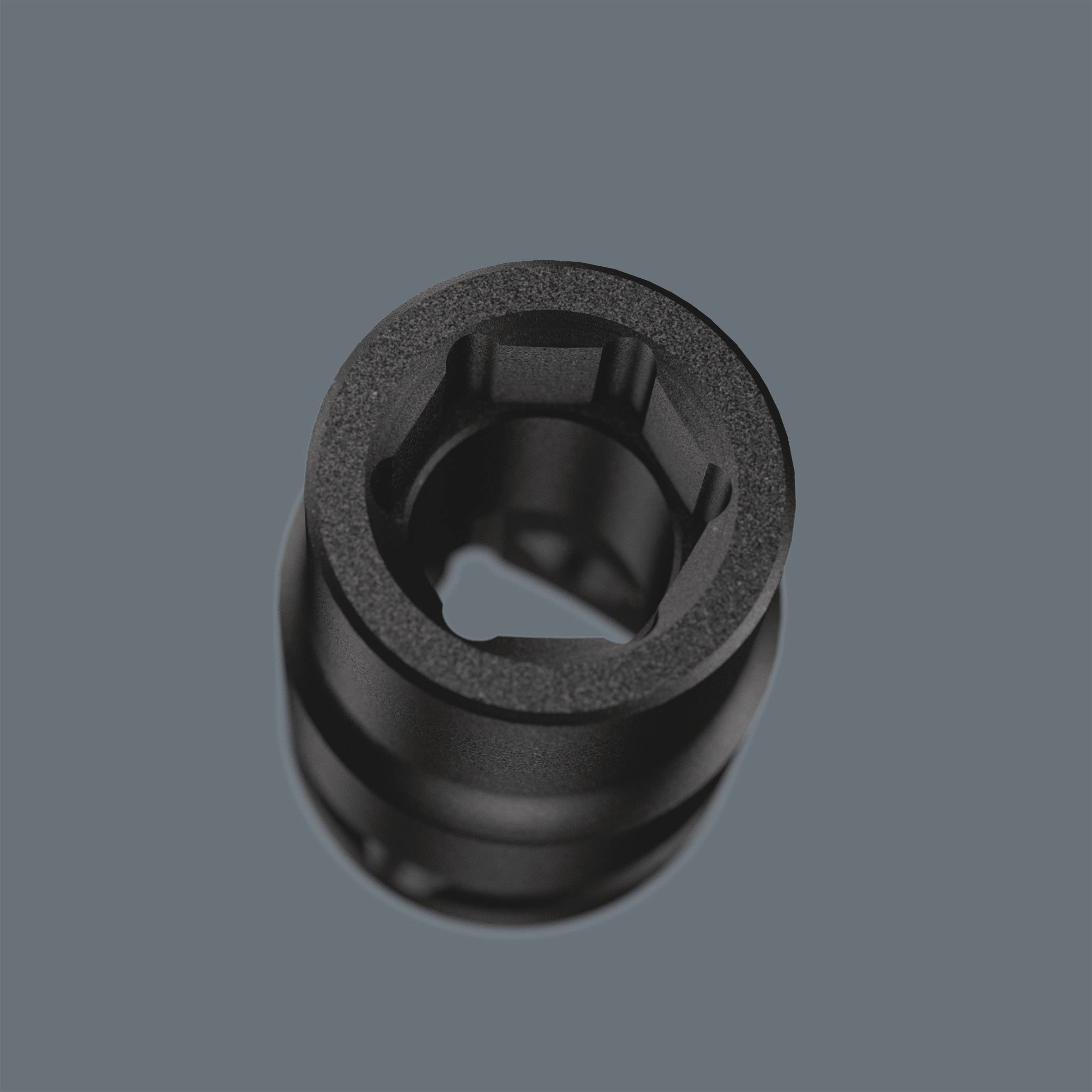 Ein schwarzes zylindrisches Objekt vor einem grauen Hintergrund. Es hat eine Öffnung in der Mitte und wirkt mechanisch.