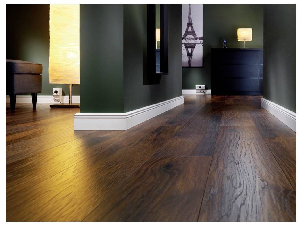Modernes Interieur mit dunklen Holzböden, dunklen Wänden, einer Stehleuchte, einer Kommode und Eiffel-Turm-Wandkunst in einem engen Flur.