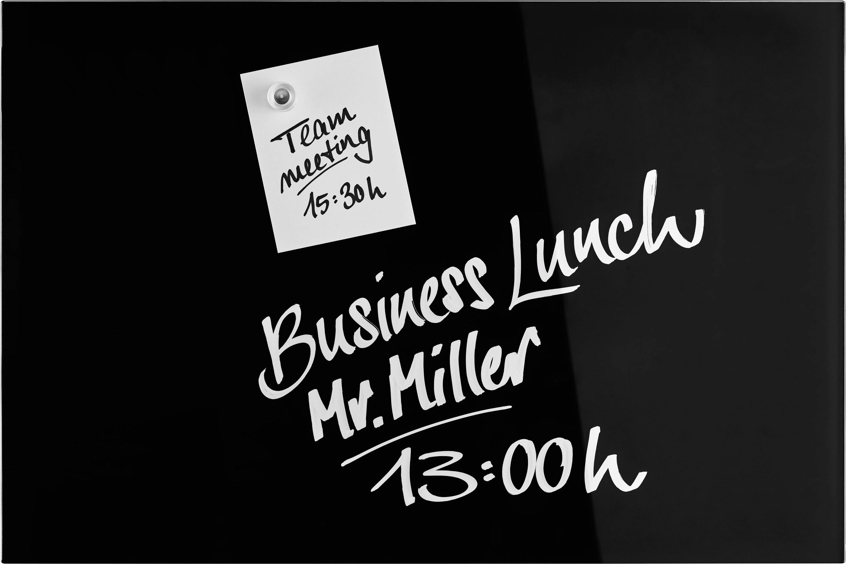 Schwarzes Brett mit Notizen: 'Team meeting 15:30h' und 'Business Lunch Mr. Miller 13:00h'.