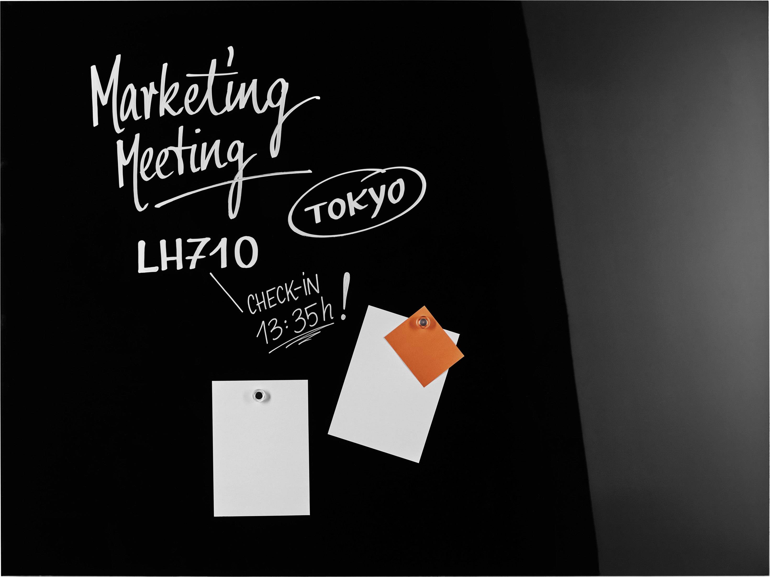 Schwarzes Brett mit der Aufschrift 'Marketing Meeting', 'Tokyo', Flug 'LH710', 'Check-in 13:35h'. Zwei leere Notizzettel befestigt.