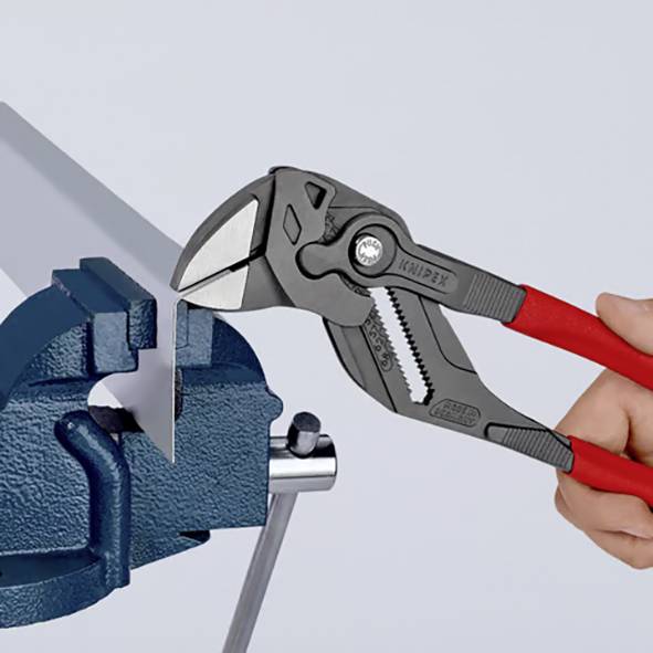 Person hält eine Zange und klemmt ein Stück Metall in einem Schraubstock. Die Zange schneidet das Metall, wobei die Kraft des Werkzeugs demonstriert wird.