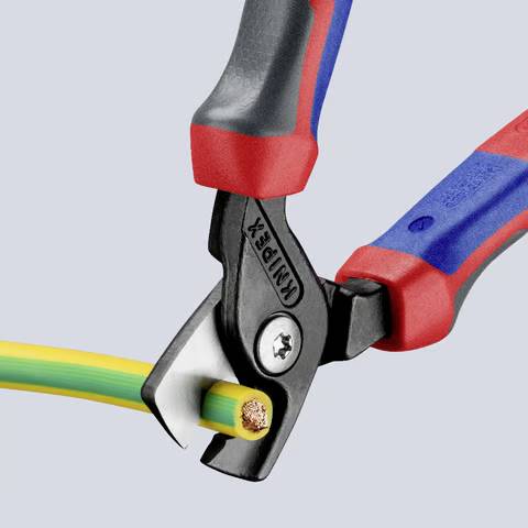 Drahtschneider, der ein grün-gelbes Elektrokabel durchtrennt und die Kupferdrähte freilegt. Schwarzes Werkzeug mit roten und blauen Griffen, Markenname sichtbar.