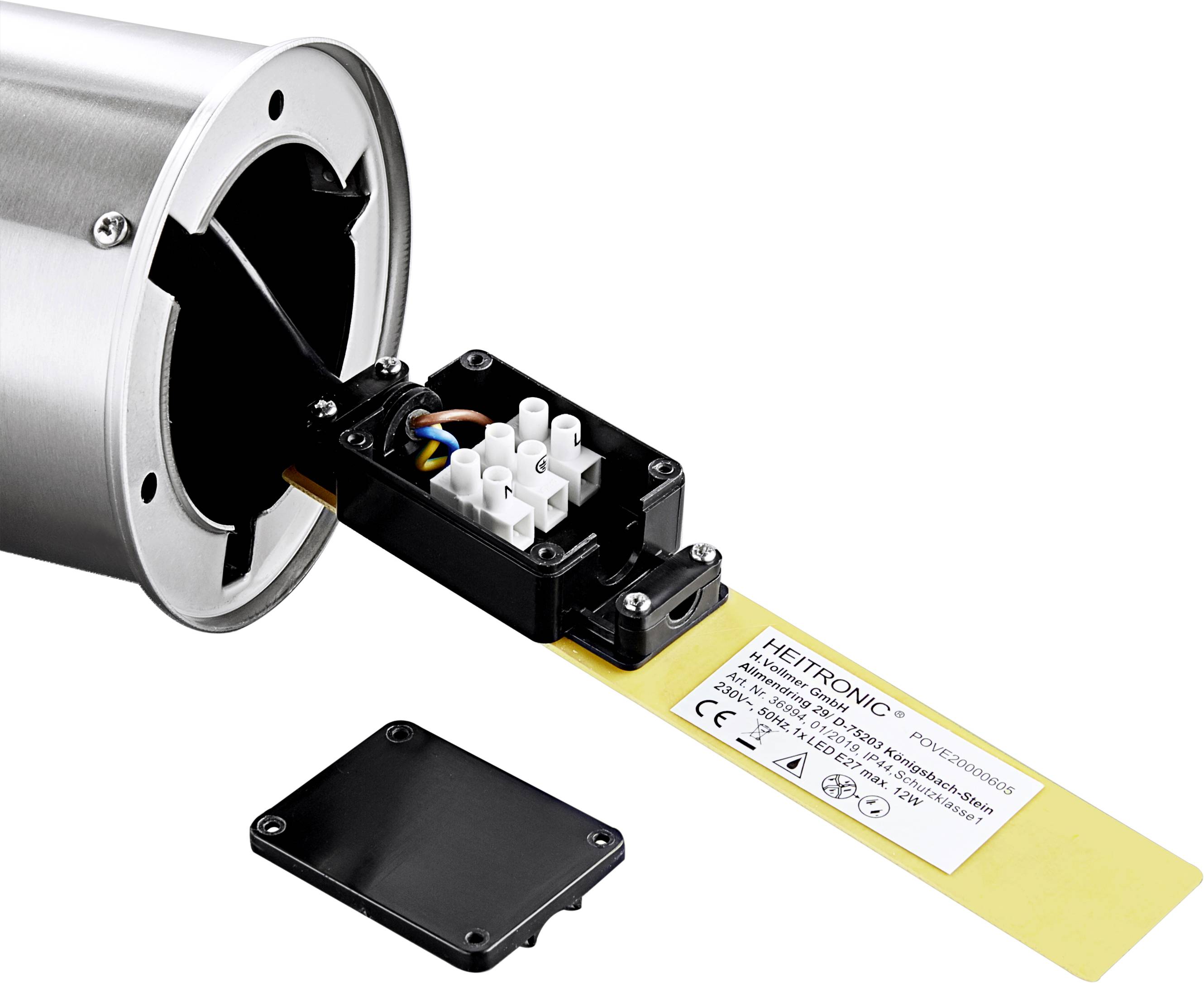 Ein elektrischer Anschlussblock mit Kabeln für eine zylindrische Metallvorrichtung. Eine Abdeckung liegt daneben.