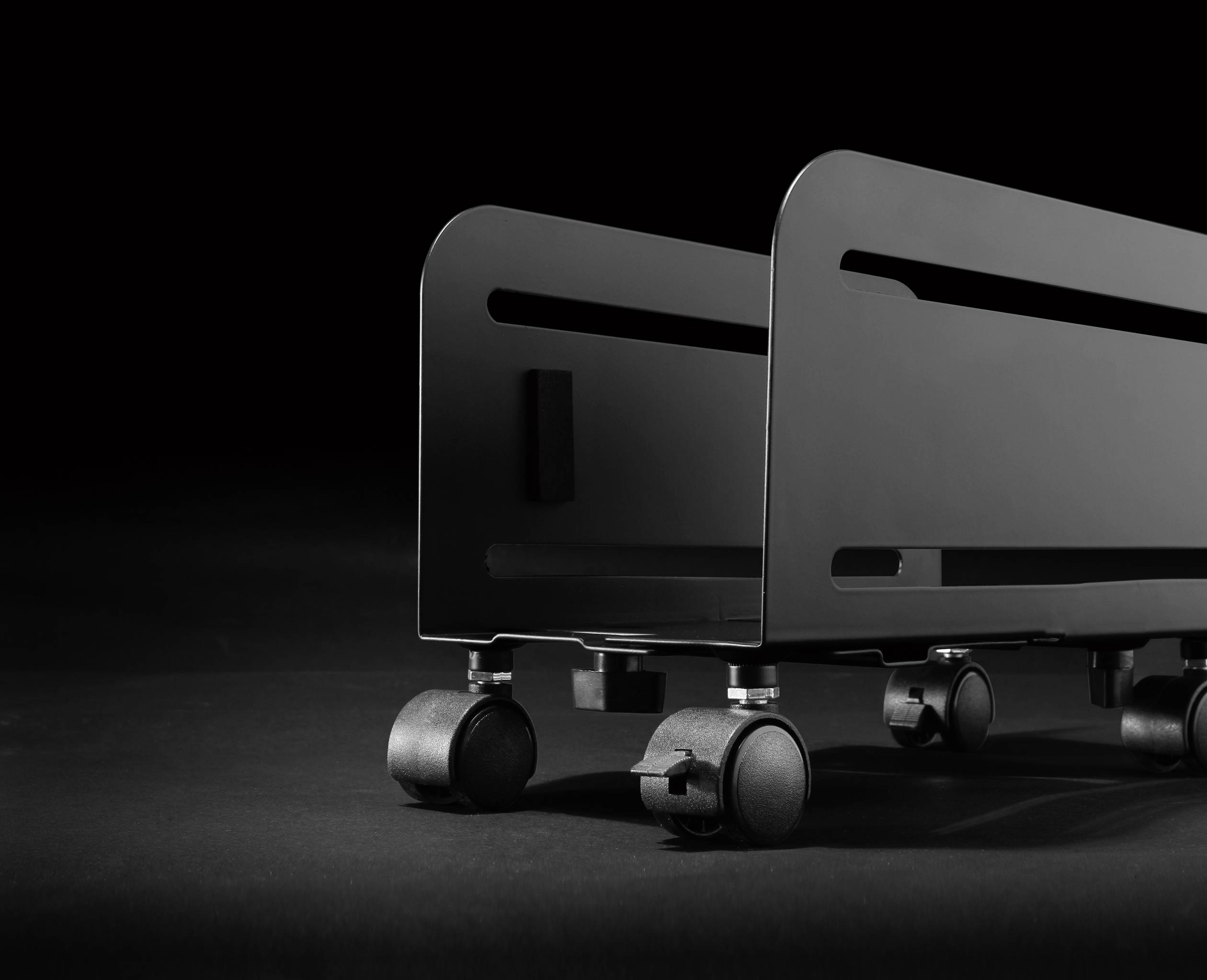 Ein schwarzer, minimalistischer Rollcontainer auf Rädern vor einem dunklen Hintergrund. Designbetont, industrieller Stil.