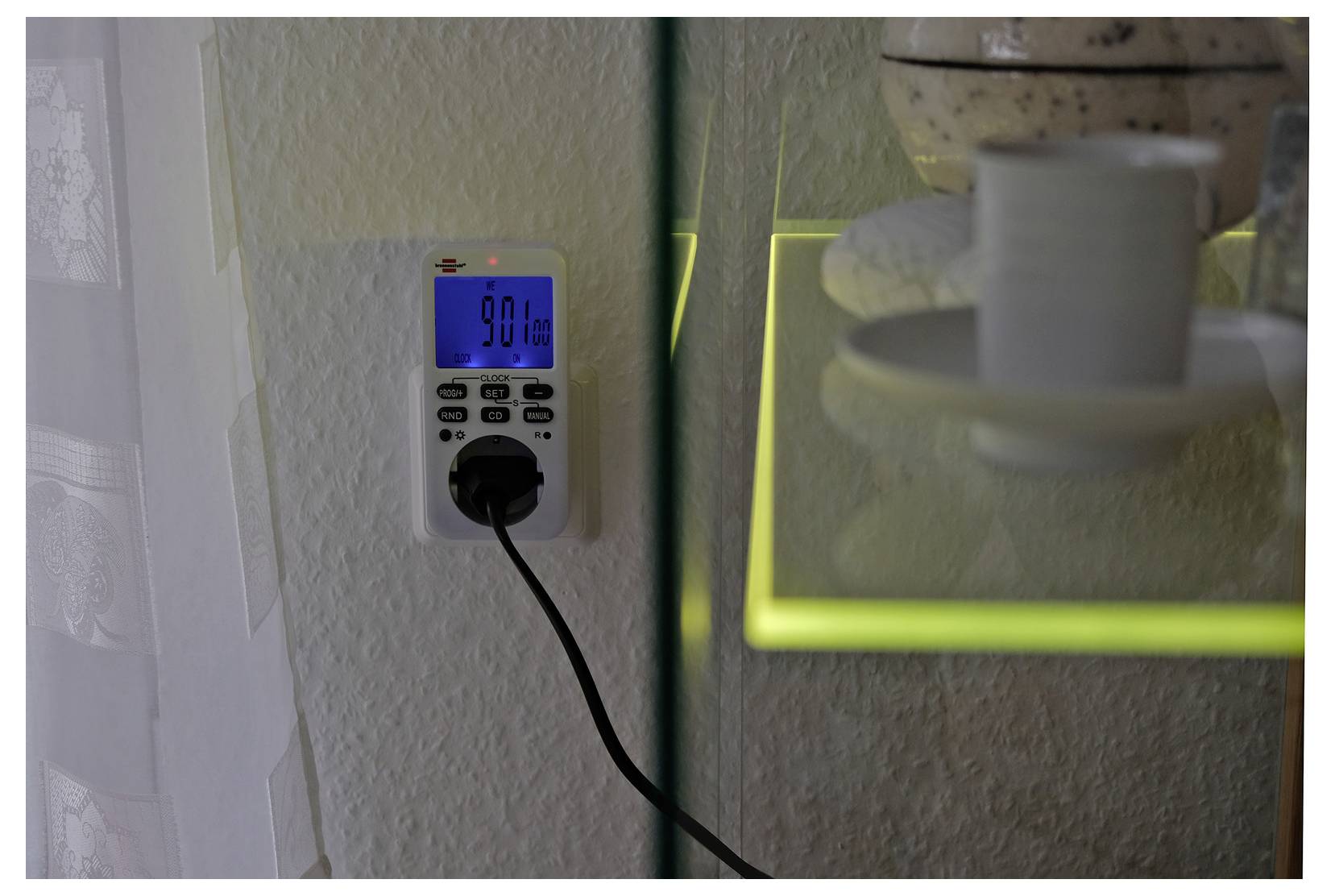 Eine Wandsteckdosen-Zeitschaltuhr mit blauem digitalen Display, das auf 9:01 Uhr eingestellt ist, mit einem eingesteckten Stecker und baumelndem Kabel.