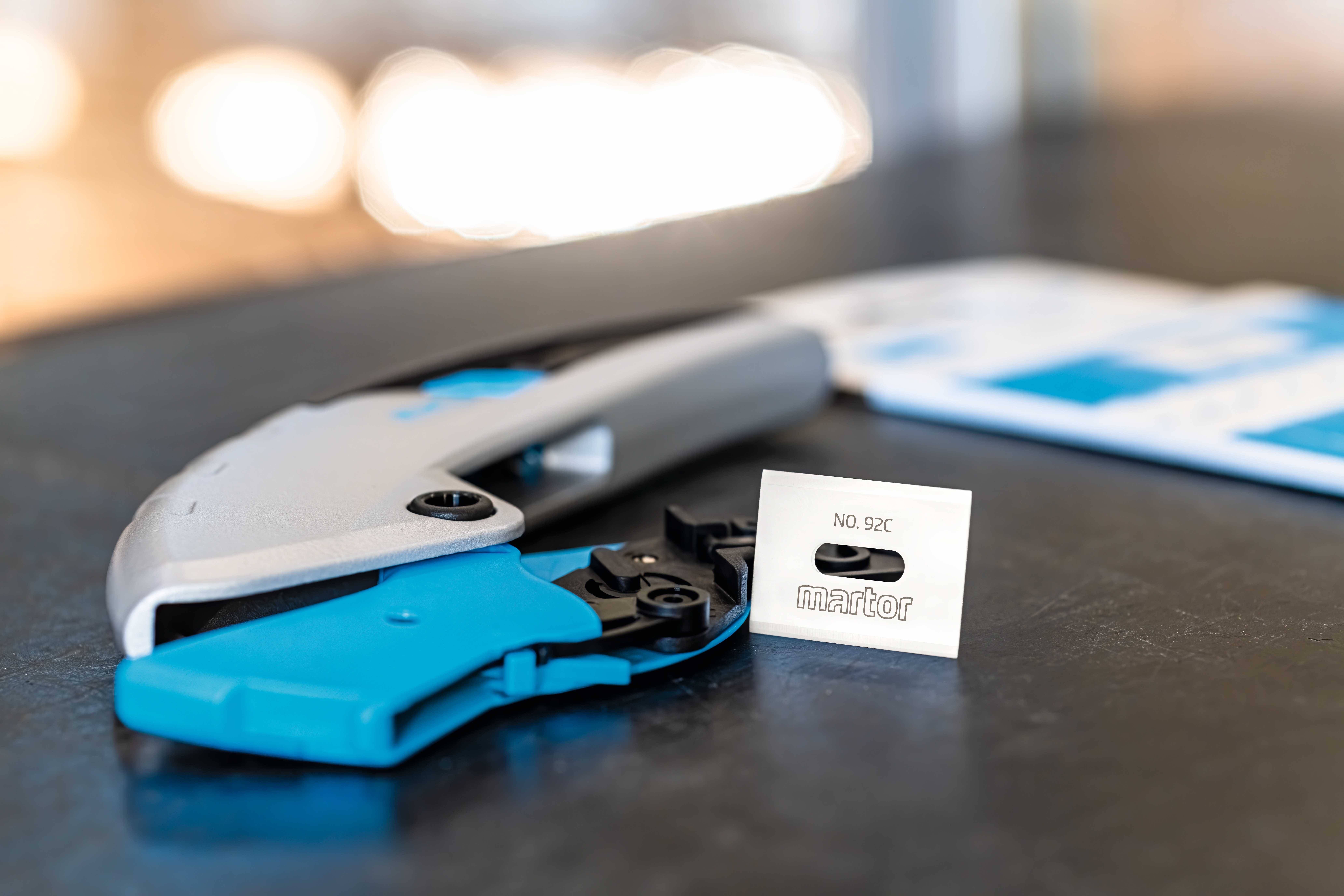 Ein blaues und silbernes Werkzeug liegt auf einem Tisch neben einem Verpackungsetikett mit der Aufschrift 'No. 902'.
