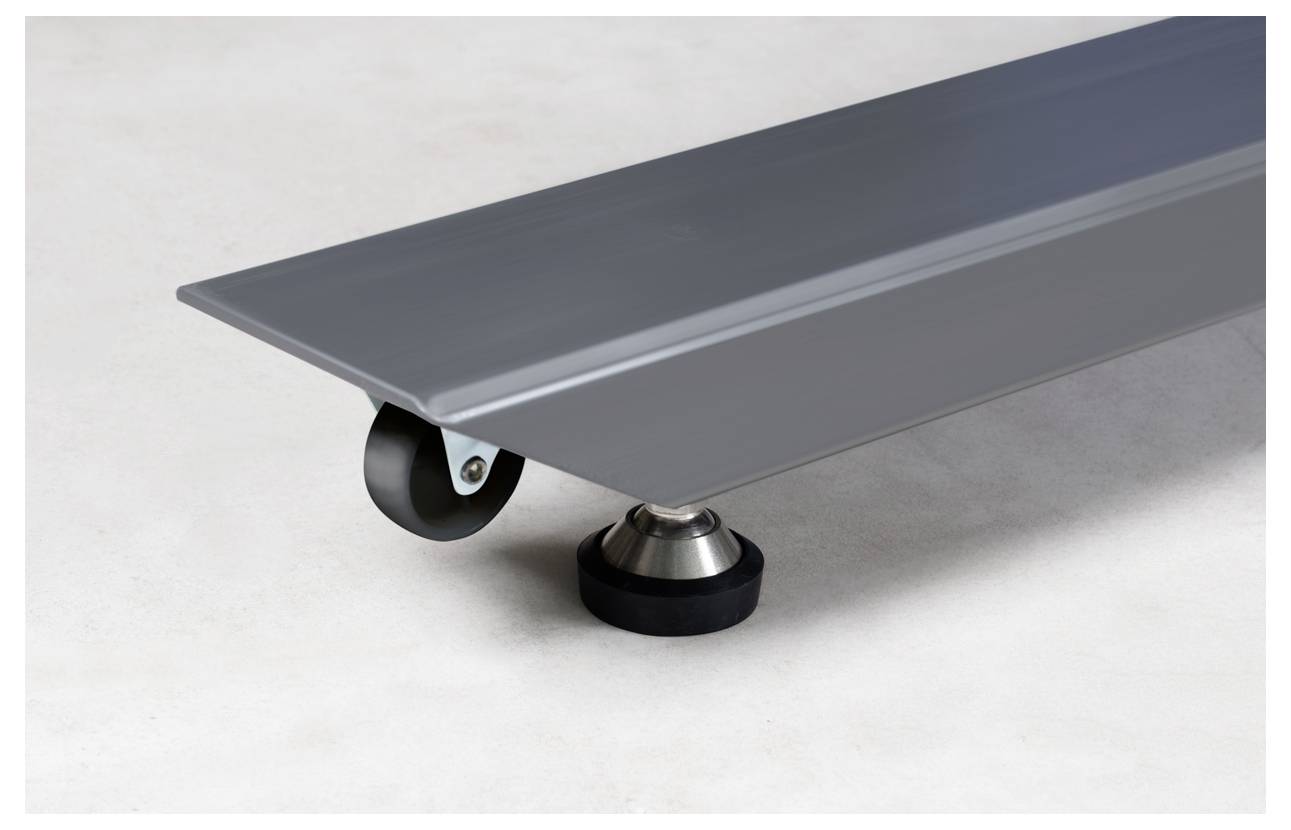 Nahaufnahme eines grauen Metallgeräts mit kleinen Rollen und einer runden, schwarzen Gummifüße auf hellem Hintergrund.