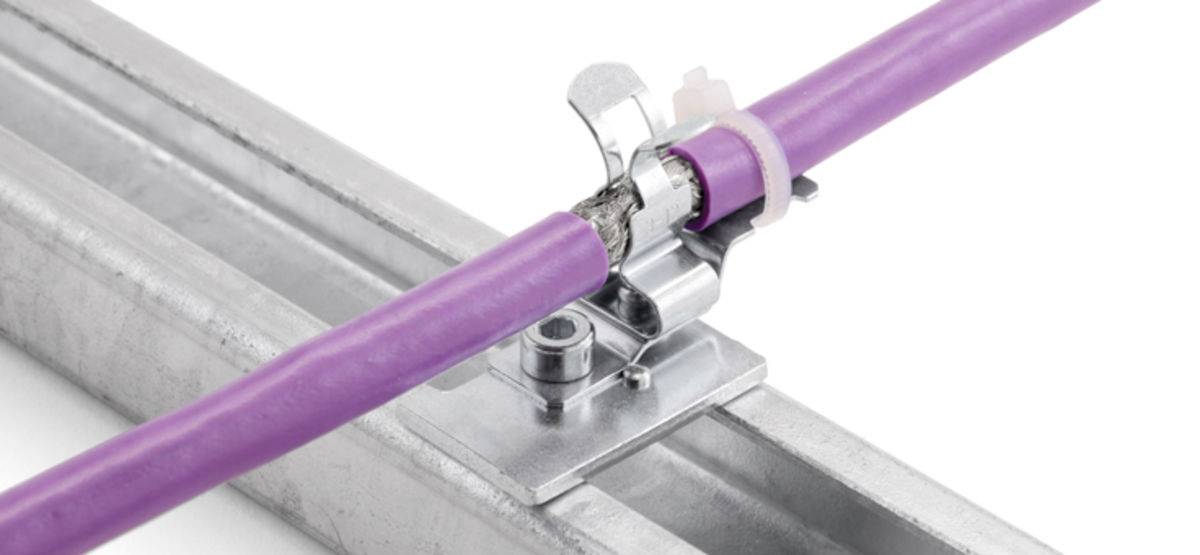 Ein violettes Kabel wird an einer Metallklammer auf einer Metallschiene befestigt.