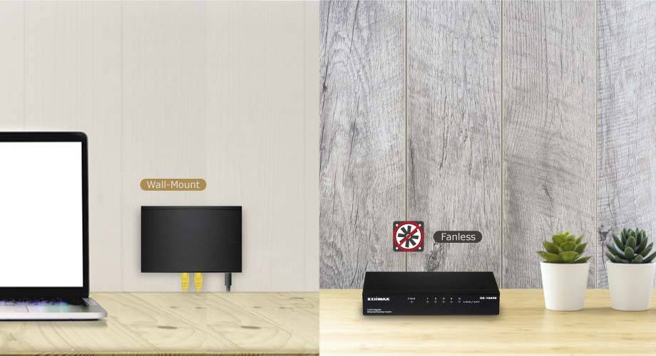 Ein Desktop mit einem Laptop links zeigt einen an der Wand montierten Router und einen lüfterlosen Netzwerk-Switch rechts, daneben stehen zwei kleine Pflanzen.