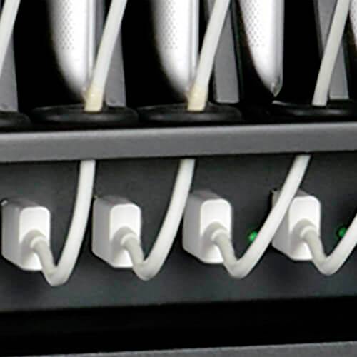 Mehrere Netzadapter sind in eine Steckdosenleiste eingesteckt, mit weißen Kabeln und leuchtenden grünen Anzeigen.