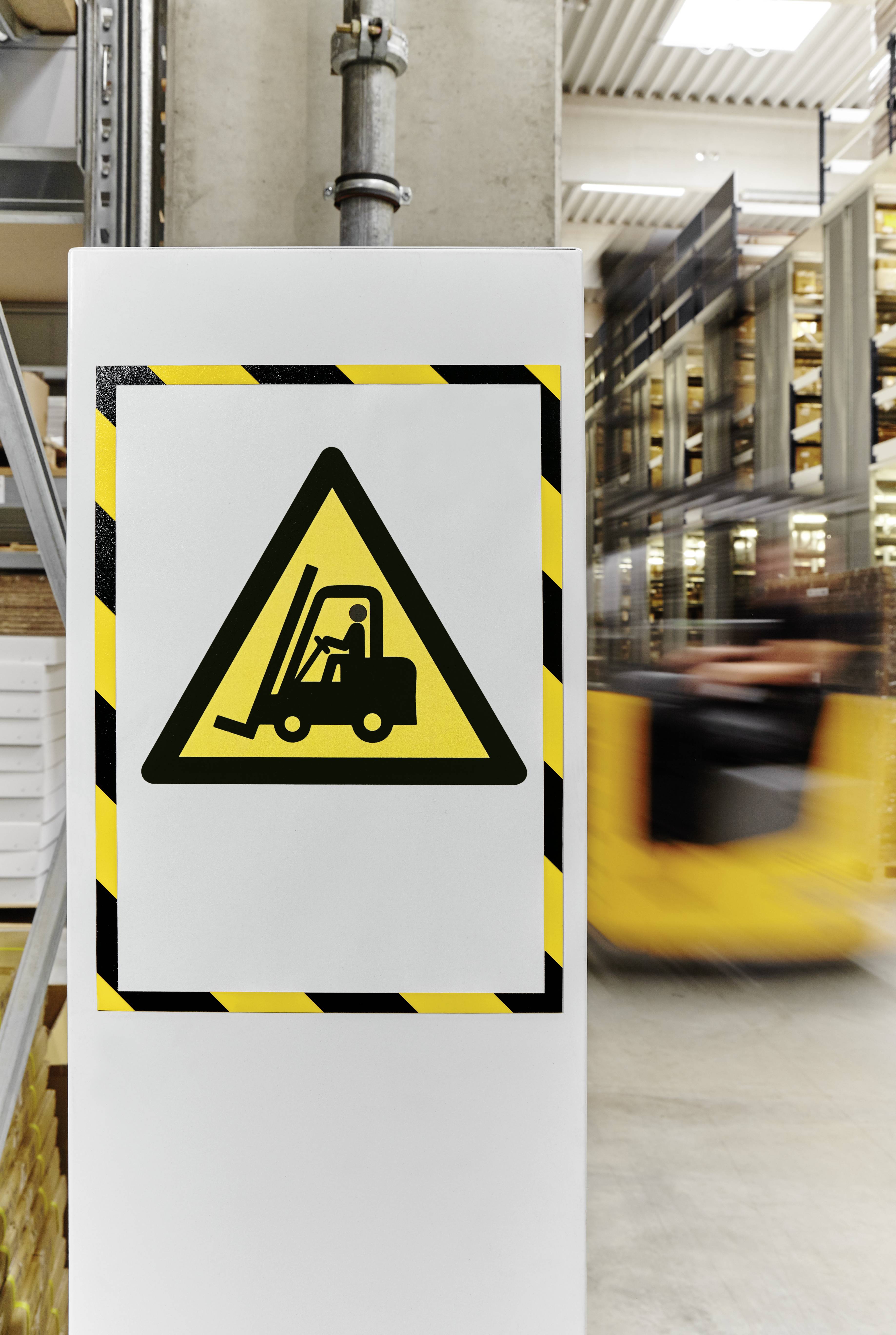 Warnschild mit Gabelstapler-Symbol in einem Lager, im Hintergrund bewegt sich ein gelber Gabelstapler schnell an Regalen vorbei.