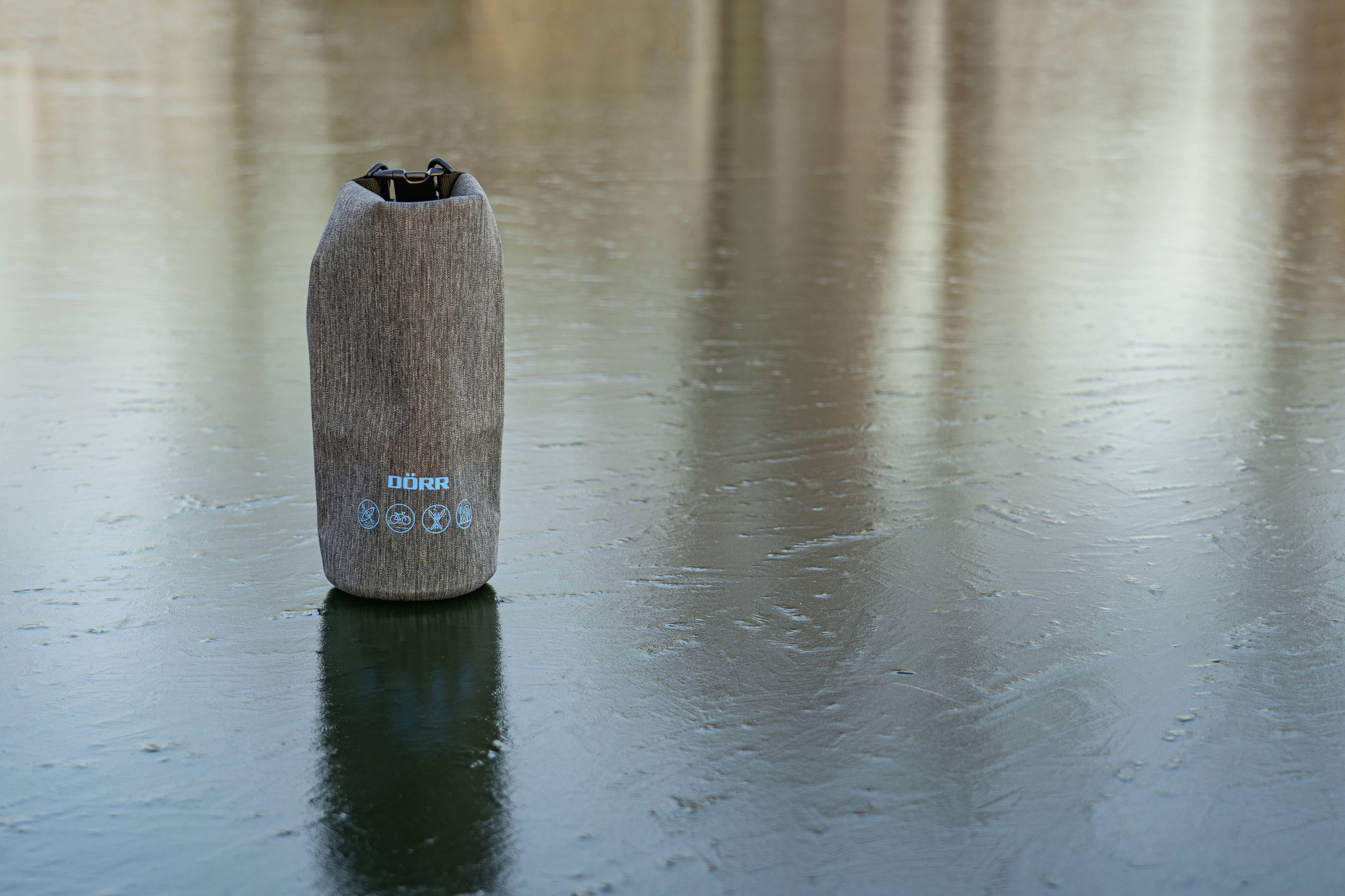 Ein isolierter Wasserbehälter, stehend auf einer glänzenden, glatten Oberfläche, mit einem dezenten blauen Logo.