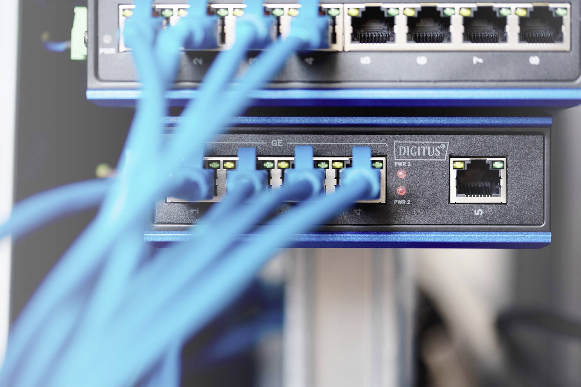 Ein Netzwerk-Switch mit mehreren angeschlossenen blauen Ethernet-Kabeln, die Datenverbindungen in einem Serverraum darstellen.