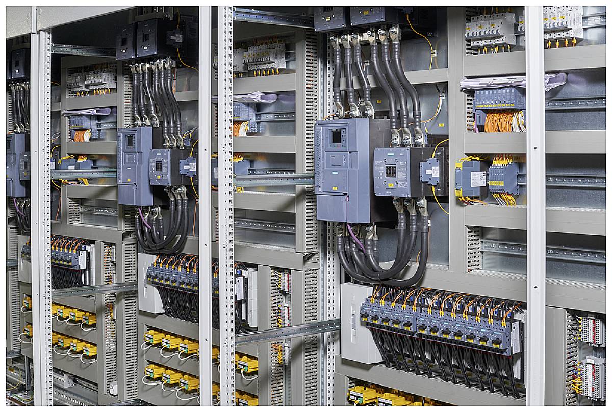 Elektrische Schalttafel mit mehreren Schaltkreisen und Kabeln, die in einem metallischen Gehäuse organisiert sind.