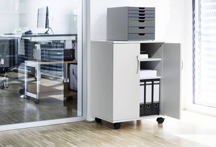 Ein grauer Aktenschrank im Büro mit geöffneter Tür zeigt Ordner und Papierfächer. Daneben ein geschlossener Aktenschrank mit Ablagefächern oben.