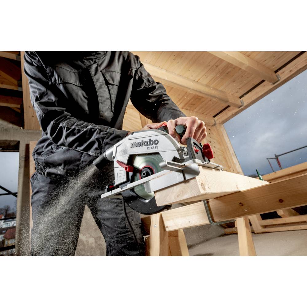 Eine Person verwendet eine Metabo-Kreissäge, um einen Holzbalken in einem teilweise fertiggestellten Gebäude mit sichtbarer Holzrahmenkonstruktion zu durchtrennen.