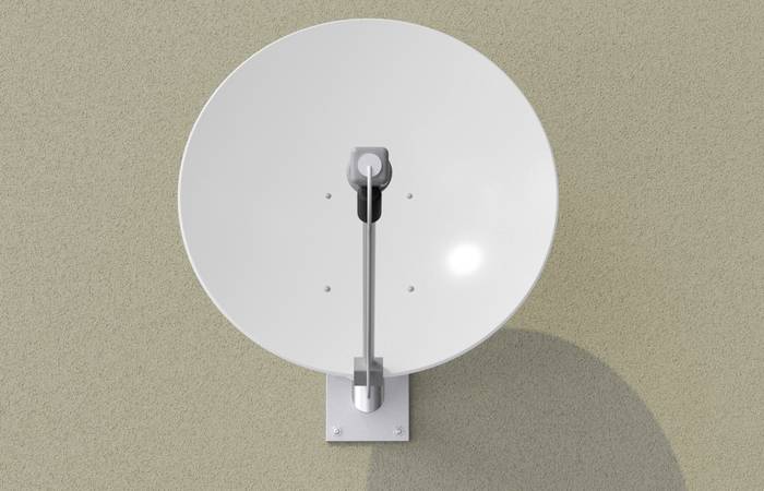 Satellitenschüssel an einer Wand montiert, mit Sonnenlicht, das einen kleinen Glanz erzeugt.